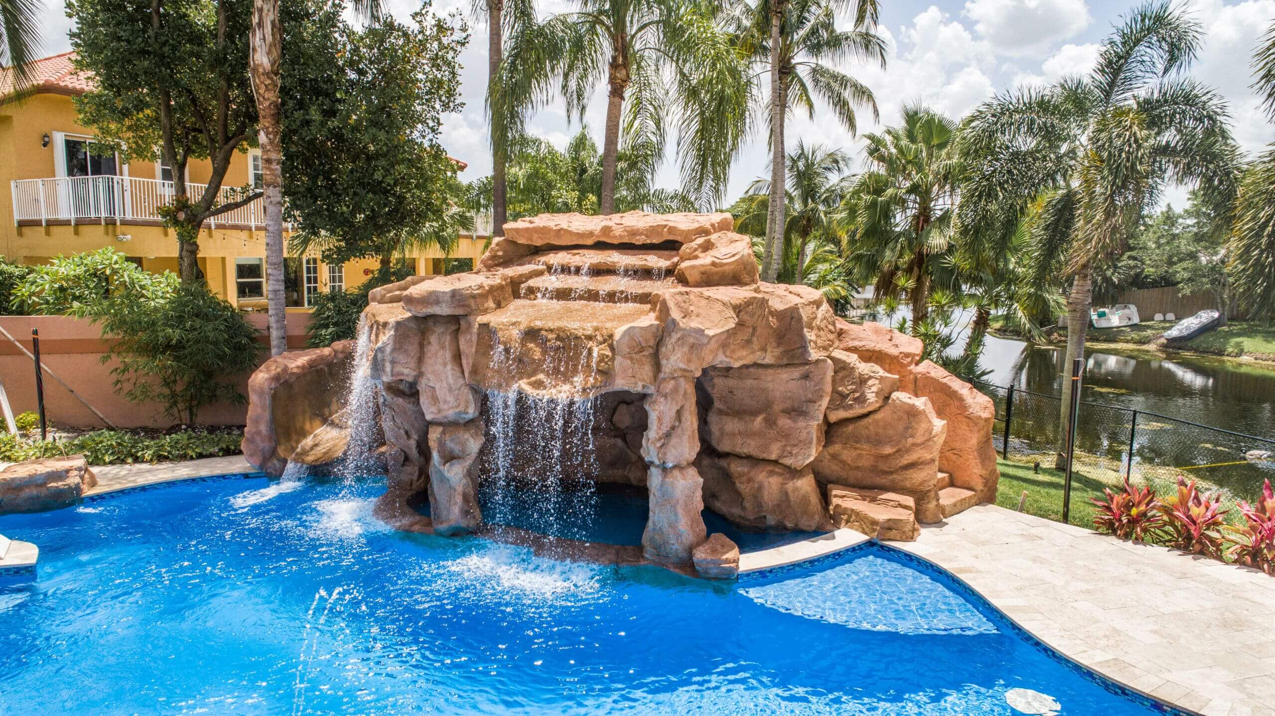 A pool with a beautiful stone waterfall and integrated hot tub