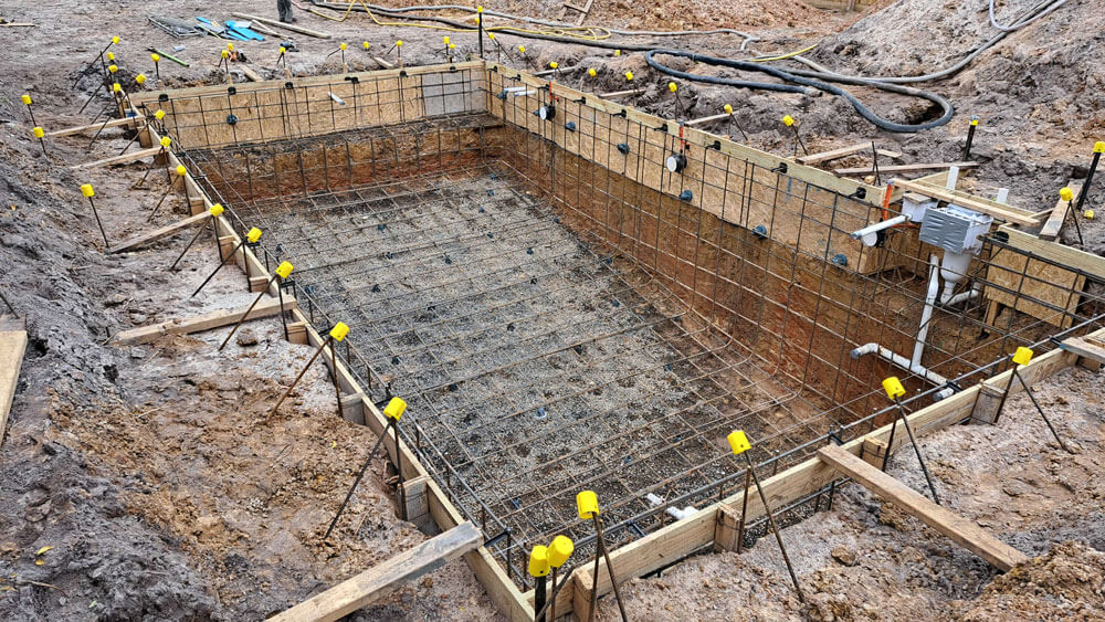 Construction workers tying reinforced steel bars for a pool frame