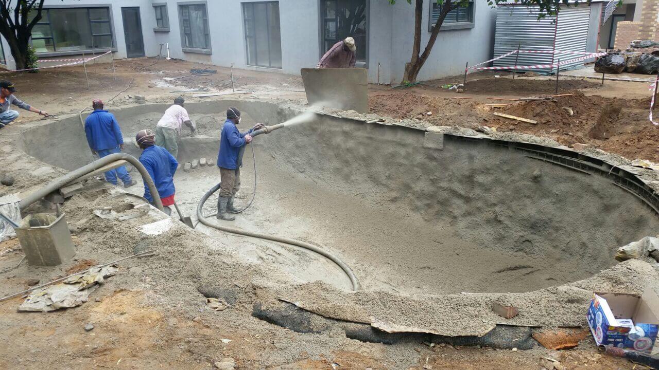 A worker applying gunite to a pool shell
